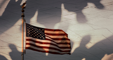 American flag waving over shadows of people