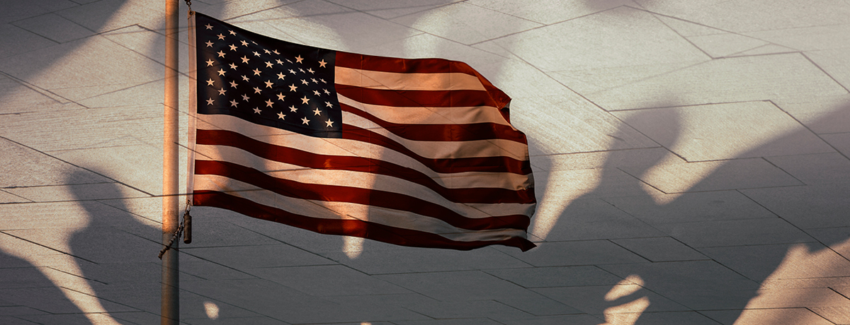 American flag waving over shadows of people