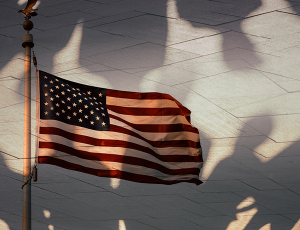 American flag waving over shadows of people