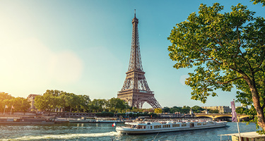 Boat crossing river in front of Eiffel Tower against blue sky