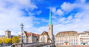Bridge over water with skyline of town in Switzerland and blue sky in background