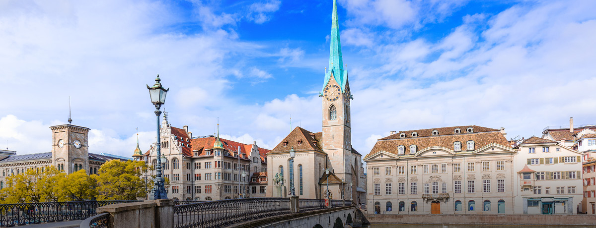 Bridge over water with skyline of town in Switzerland and blue sky in background