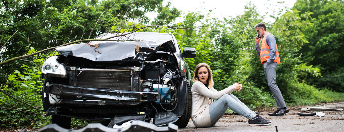 Woman beside damaged car after accident