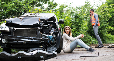 Woman beside damaged car after accident
