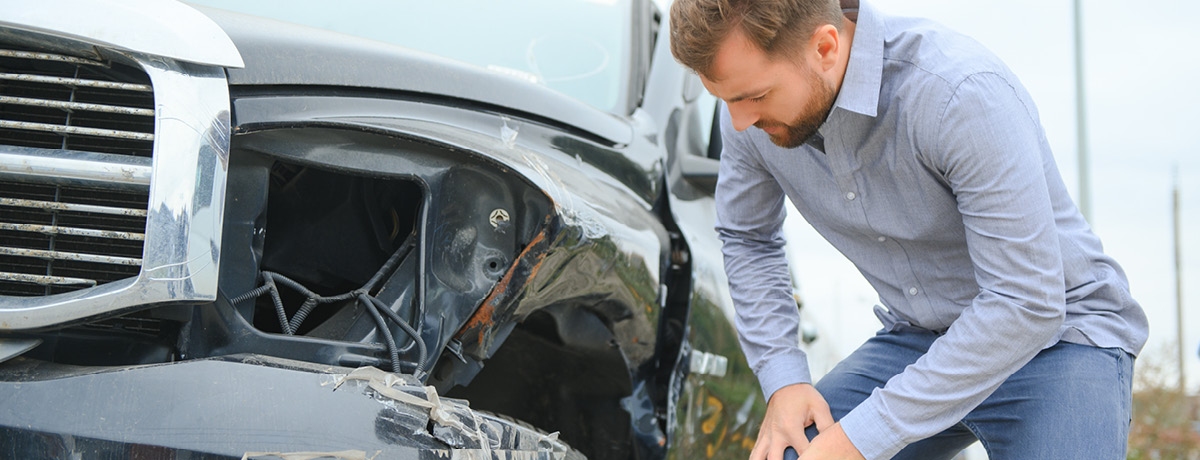  Man inspecting the damage to his vehicle following a car accident in Austin