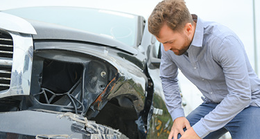  Man inspecting the damage to his vehicle following a car accident in Austin
