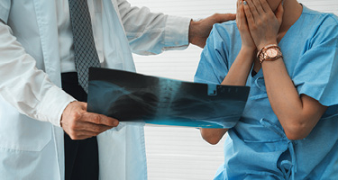 Doctor in white lab coat showing x-ray to patient in blue scrubs