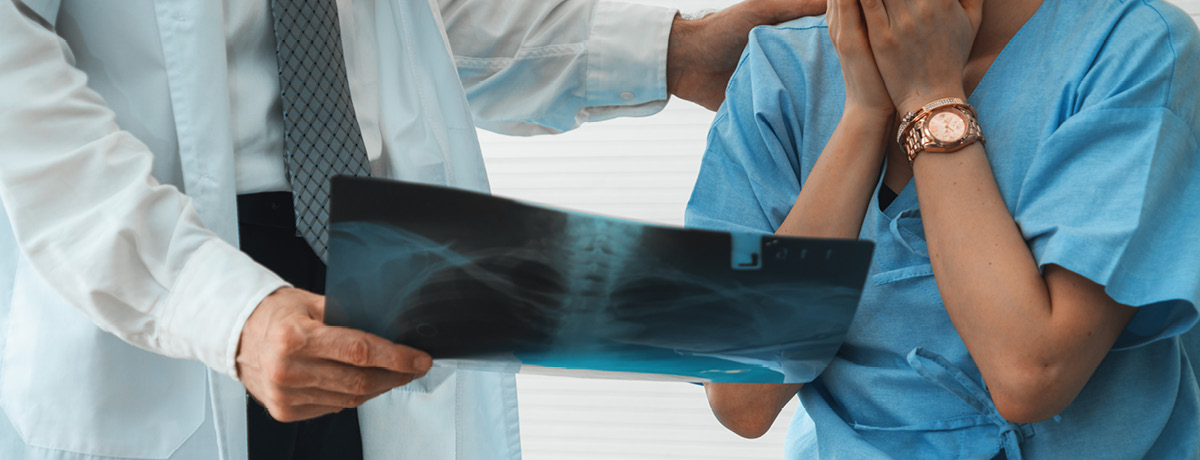 Doctor in white lab coat showing x-ray to patient in blue scrubs