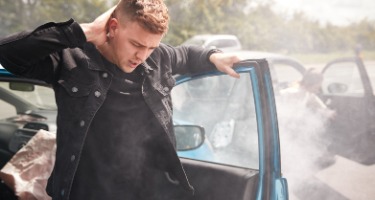 Man walks out of blue car that just got into an accident with hand on his neck