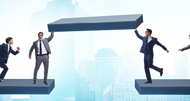 Four lawyers stand on construction beams, raising one above their heads