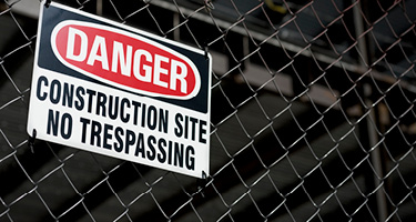 Danger construction site no trespassing sign on fence
