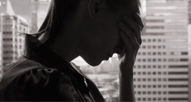 Man frustrated holds his head in defeat near a cityscape with a grey and white filter