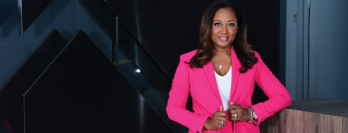 Woman wearing pink suit standing against desk