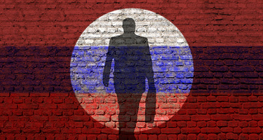 Shadow figure in spotlight against red and blue brick wall