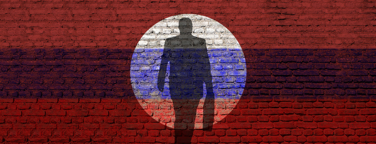 Shadow figure in spotlight against red and blue brick wall