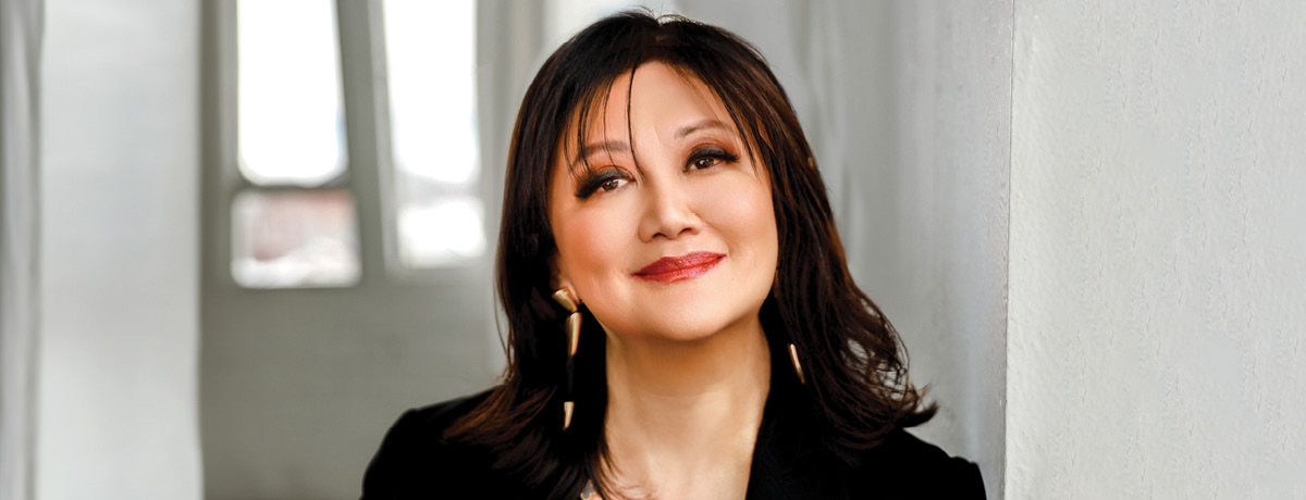 Deborah in gold jewlery ahite background and black top 