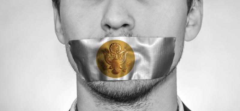 Businessman with silver duct tape with the bronze presidential seal on his mouth