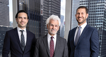 Three lawyers wearing suits pose for a picture