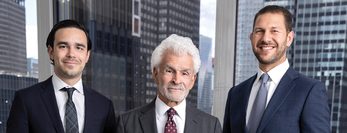 Three lawyers wearing suits pose for a picture