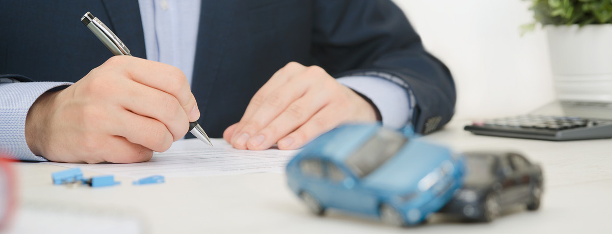 Man at desk writing with two toy cars in front of him