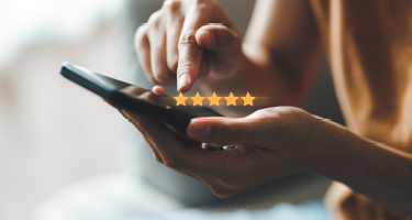 Hands holding smartphone with fives stars above phone