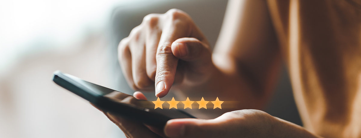 Hands holding smartphone with five stars above phone