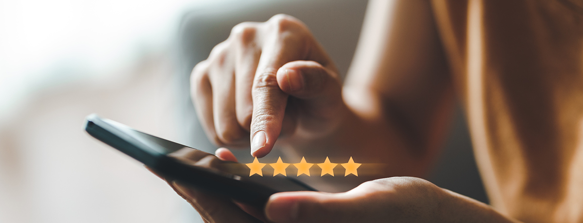 Hands holding smartphone with fives stars above phone