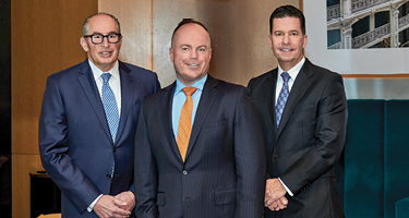 Three men in business suits standing in office