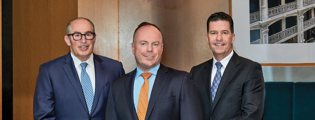Three men in business suits standing in office