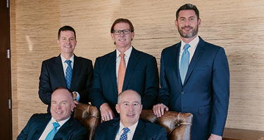 Five lawyers sit and stand posing for a photo