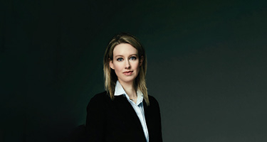 Woman in suit pictured alone with black background