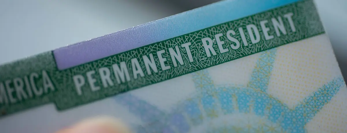 Close-up of a U.S. Permanent Resident Card showing the text 'PERMANENT RESIDENT'
