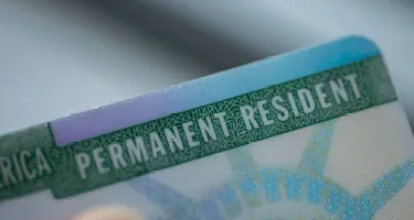 Close-up of a U.S. Permanent Resident Card showing the text 'PERMANENT RESIDENT'