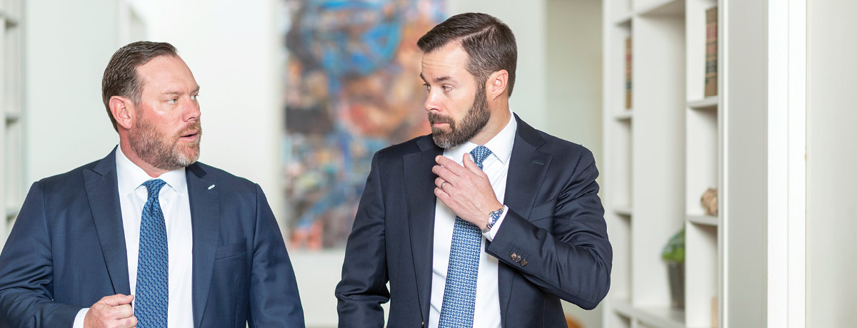Two suited lawyers walk side by side while talking