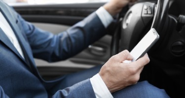 A man in a suit using his phone while driving