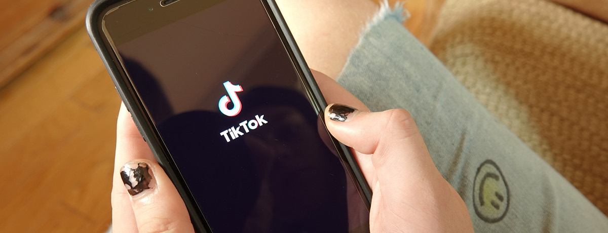 A person holds a smartphone displaying the TikTok logo