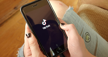 A person holds a smartphone displaying the TikTok logo