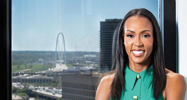 Woman in green dress crossing her arms and posing for headshot