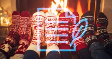 Holiday season with four people wearing Christmas socks by a fire with a paper and feather symbol