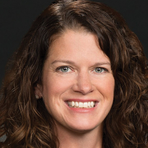 Woman with dark hair and suit smiling