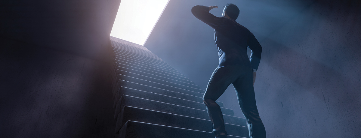 Suited man ascending staircase to overexposed exit