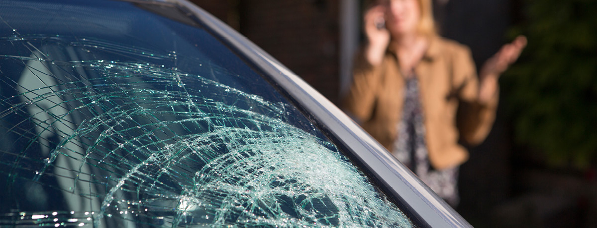 Woman on phone looking at cracked windshield