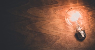 A glowing light bulb resting on a wooden table