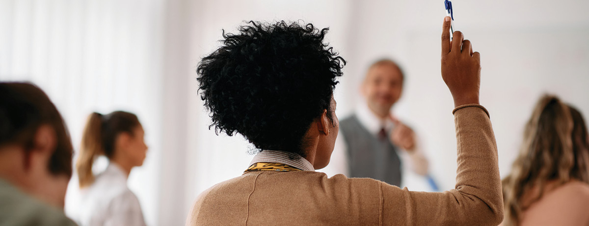 Student raising hand in classroom of other students