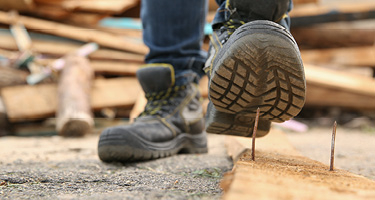 Worker on construction site steps on nail