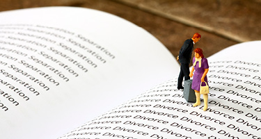 Two small figurines standing on an open divorce law book