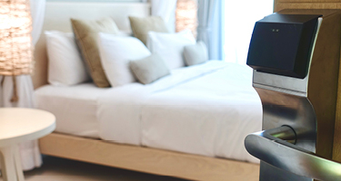 Door opening to a hotel room showing a neatly made bed