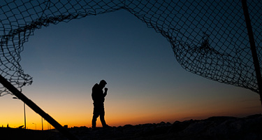 Shadow of person standing by broken chain link fence