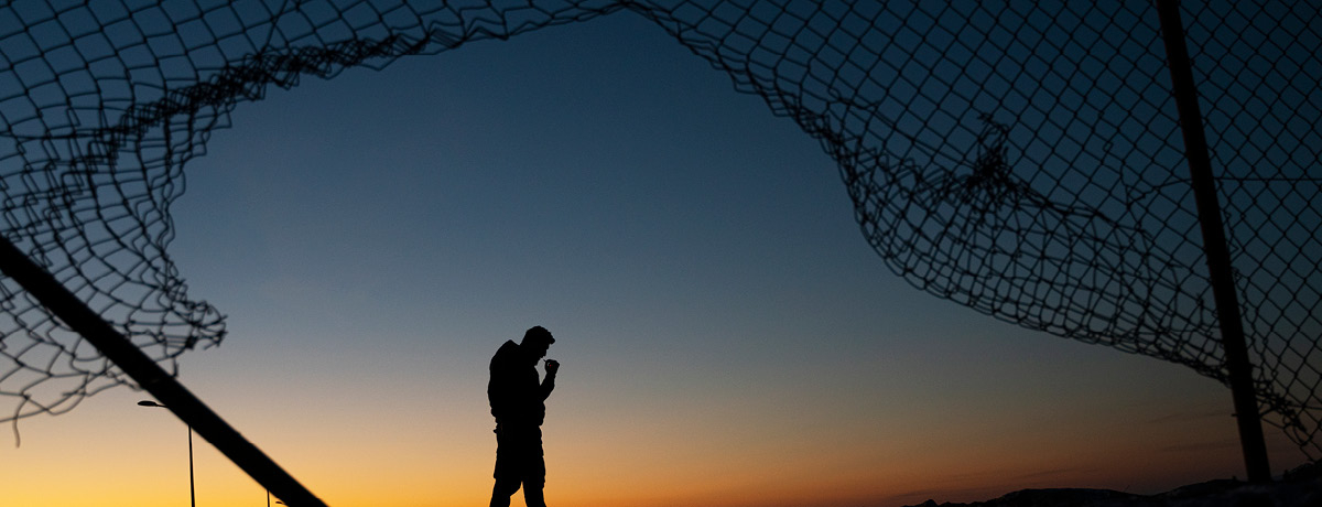 Shadow of person standing by broken chain link fence