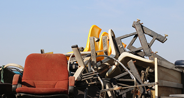 Pile of old chairs and office equipment with blue backdrop